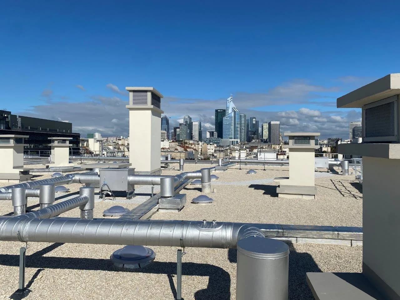 Gaines de ventilation et caisson d'extraction sur une toiture-terrasse, avec vue sur La Défense