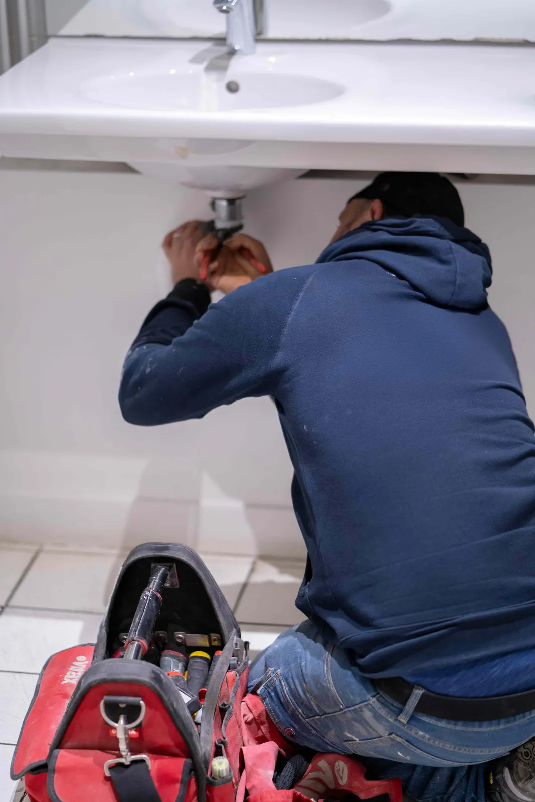 Plombier réparant l'évacuation d'un lavabo