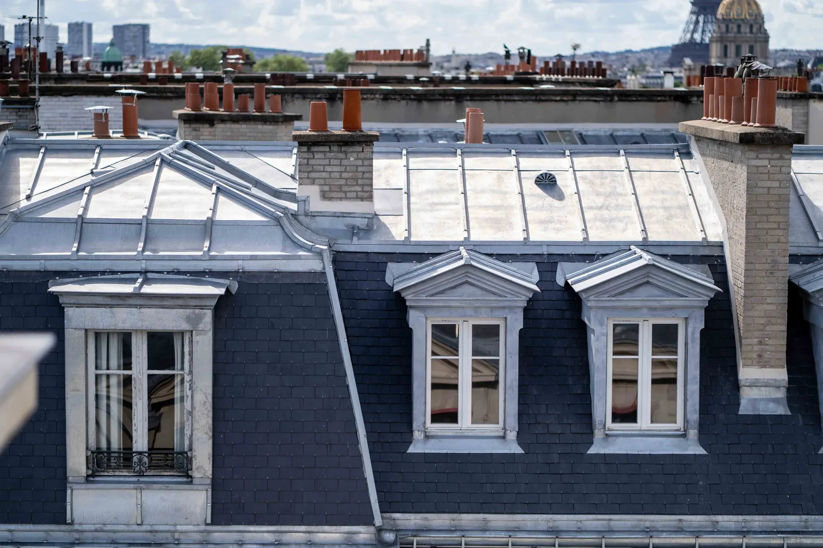Toiture d'immeuble parisien en zinc et ardoise avec lucarnes et souches de cheminée
